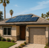 Modern California home with rooftop solar panels installed, surrounded by palm trees and drought-tolerant landscaping under a clear blue sky.