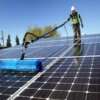 A professional cleaning solar panels on a residential rooftop in Los Angeles