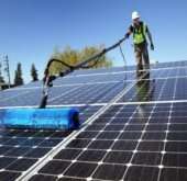 A professional cleaning solar panels on a residential rooftop in Los Angeles