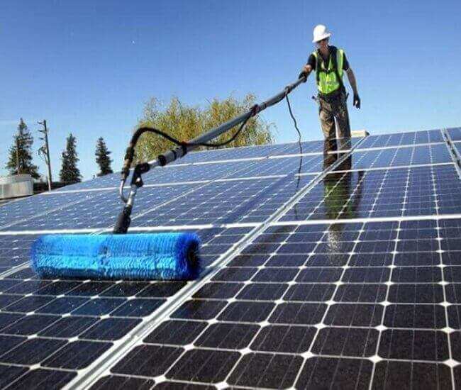 A professional cleaning solar panels on a residential rooftop in Los Angeles