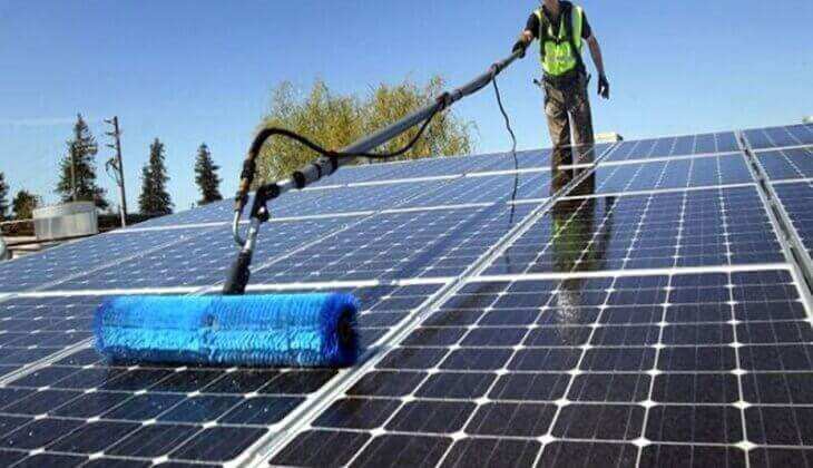 A professional cleaning solar panels on a residential rooftop in Los Angeles